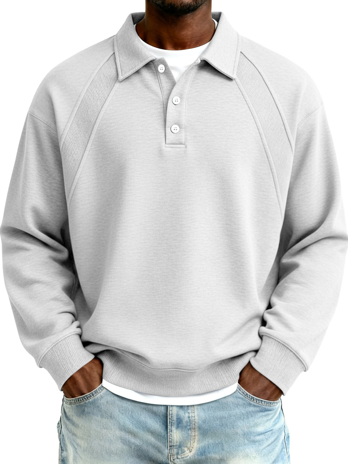 Person wearing a gray sweatshirt over a white shirt with blue jeans on a white background
